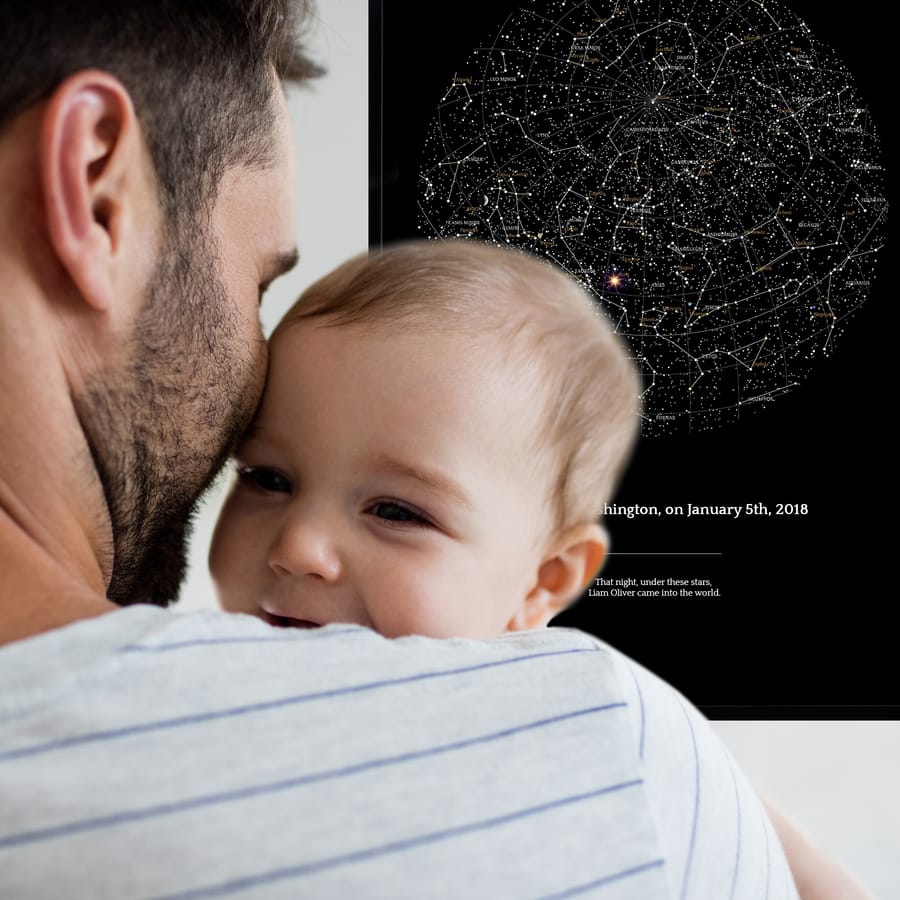 A young dad with a baby in front of the star map commemorating the baby’s birth